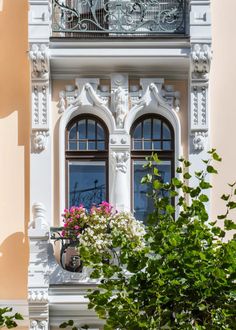 an ornate balcony with potted plants and flowers in front of the window sill