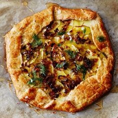 a pizza sitting on top of a table covered in cheese and toppings with herbs