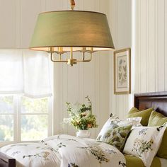 a bed sitting under a light hanging from a ceiling fixture above it's headboard