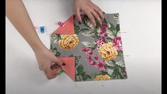 someone is cutting out fabric with scissors on top of a piece of cloth that has flowers on it