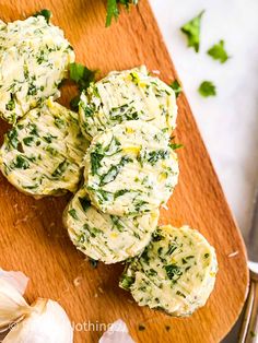 some food is sitting on a cutting board next to garlic and parmesan cheese