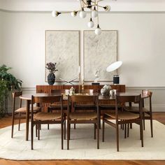 a dining room table surrounded by chairs and artwork