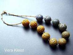 a necklace made out of different colored beads on a silver background with the words vera kleit written below it