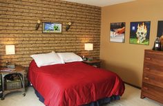 a bedroom with a brick wall and red bed spread on top of the bedspread