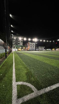 an empty baseball field at night with lights on the stands and grass in the outfield