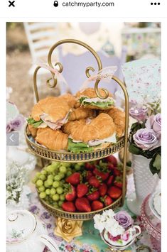 two tiered trays filled with sandwiches and strawberries on top of a table