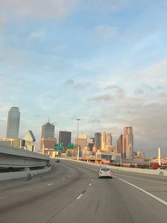 cars driving down an interstate with city skyline in the background