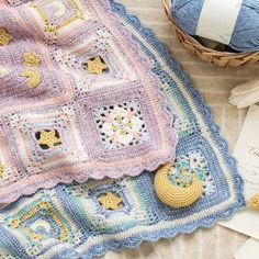 a crocheted blanket sitting on top of a table next to a ball of yarn