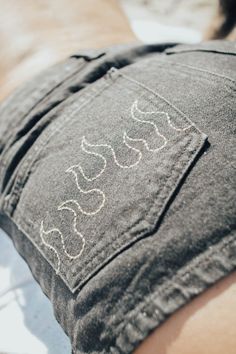 the back of a person's jeans with white writing on it and a dog laying in the background