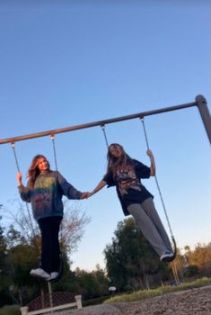 two girls are swinging on a swing set