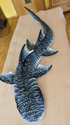 a sculpture of a whale laying on top of a bed in a room with wooden floors