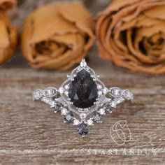 a black diamond ring sitting on top of a wooden table next to roses and flowers