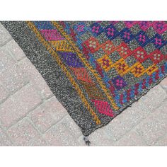 a multicolored area rug on the ground with bricks in the backround