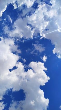 an airplane is flying in the sky with white clouds and blue sky behind it,