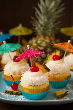 pineapple cupcakes with white frosting and cherries on a blue plate