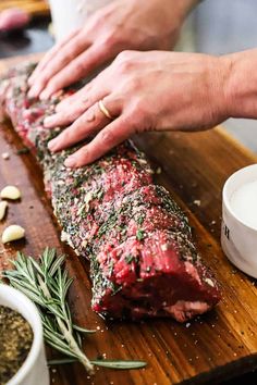 a person is cutting up some meat on a wooden board with spices and seasoning