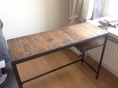 a wooden table sitting on top of a hard wood floor next to a white wall