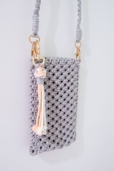 a crocheted purse hanging on the wall with a tassell and keychain