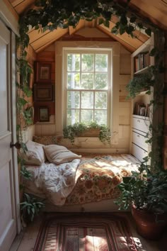 a bed sitting under a window in a bedroom next to a rug and potted plants