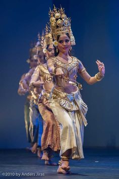 a group of people that are standing on a stage with costumes and headdress