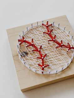 a tennis racket with red and white strings attached to it on top of a wooden board