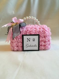 a pink rose box with a name tag on it and a ribbon around the top