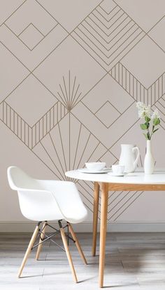 two white chairs sitting at a table in front of a wall with geometric designs on it