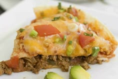 a piece of pizza on a plate with avocado and tomatoes