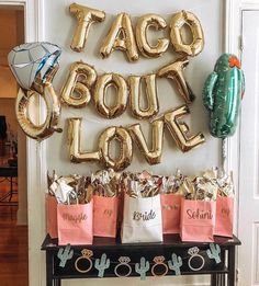 taco bout love balloons are on display in front of a table filled with bags