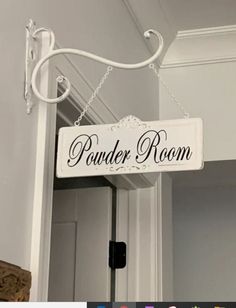 a white sign hanging from the side of a door that says powder room on it