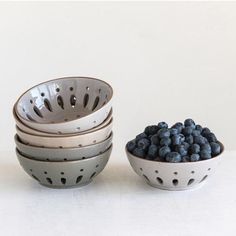 four bowls filled with blueberries sit next to each other