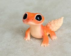 a small toy frog with big eyes sitting on the ground