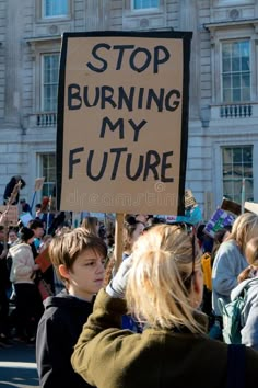 a group of people holding up signs in front of a building that says stop burning my future