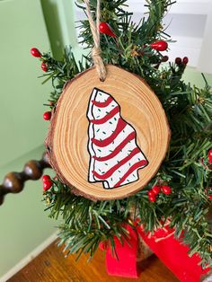 a wooden ornament with a christmas tree decoration on it's side hanging from a red ribbon