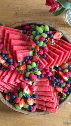 watermelon, grapes, and strawberries are arranged in a bowl on a table