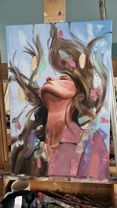 a painting of a woman with her hair blowing in the wind on an easel