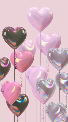 there are many heart shaped balloons in the shape of hearts hanging from strings on a pink background