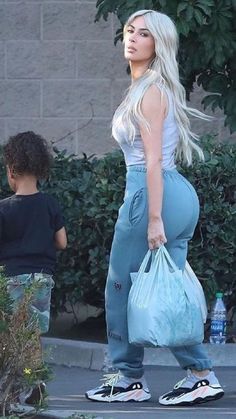 a woman with long blonde hair carrying a blue bag while standing next to a young boy