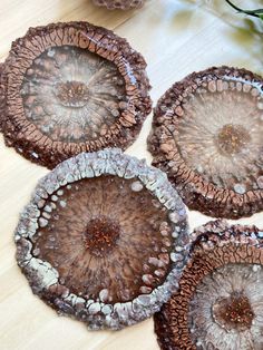 four brown and white plates sitting on top of a wooden table next to a vase