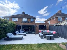 a patio with couches and tables in front of a house