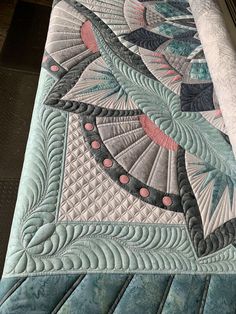 a close up view of a quilt on a bed with an intricate design in the center