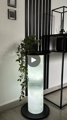 a potted plant sitting on top of a black stand next to a white wall