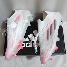 a pair of white and pink adidas shoes sitting on top of a black box