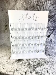 shot glasses are lined up on a white board with the word shots written in cursive writing