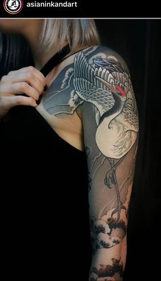 a woman's arm with a bird tattoo on it and clouds in the background