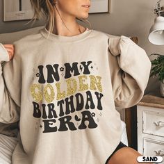 a woman wearing a sweatshirt with the words in my golden birthday era printed on it