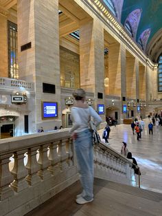 people are walking around in the lobby of a large building with high ceilings and columns