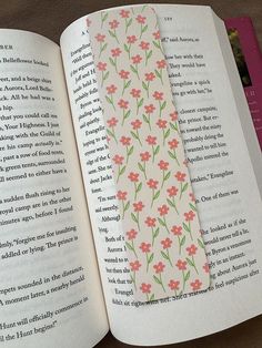 an open book with pink flowers and green leaves on the pages, next to another bookmark