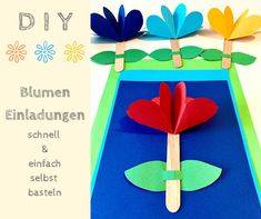 the paper flowers are placed on sticks in front of an empty blue surface with text that reads diy