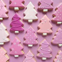 many decorated cookies are displayed on a pink surface